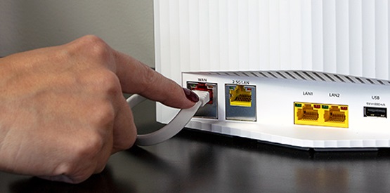 En hand som sätter in en kabel i en router